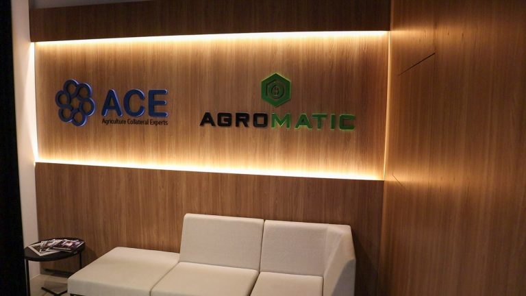 Sala de espera da Agromatic com sofás claros sob os logos Agromatic e ACE